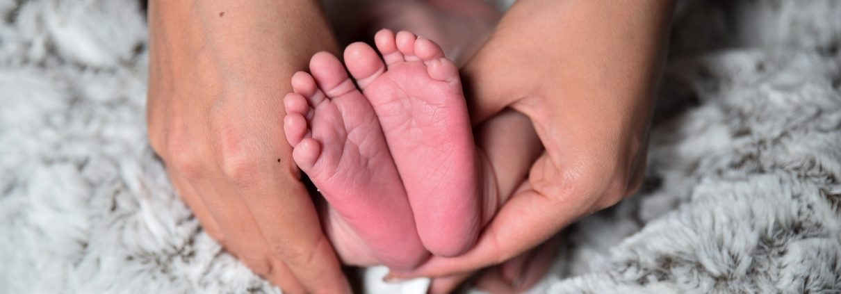 Füße eines Neugeborenen in der Hand der Mutter