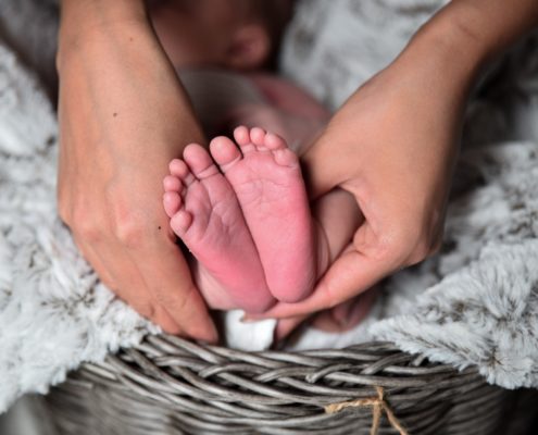 Füße eines Neugeborenen in der Hand der Mutter