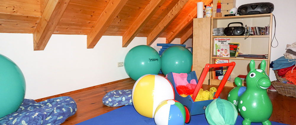 Hebammen-Kurszimmer mit buntem Spielzeug, Musik und Bodenmatten