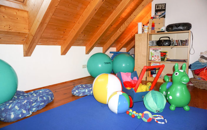 Hebammen-Kurszimmer mit buntem Spielzeug, Musik und Bodenmatten